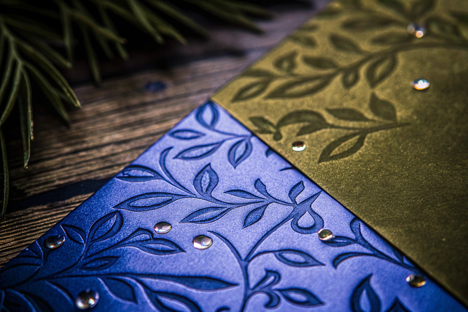 Detailaufnahme einer eleganten Einladungskarte mit einem Blattmotiv in Grün und Gold. Elegante Einladungskarte mit Blattmotiv