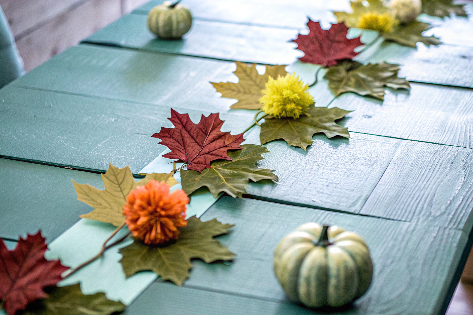 Detailaufnahme einer herbstlichen Tischdekoration mit Ahornblatt-Girlanden und Seidenpapier Pompons. Herbstliche Tischdekoration