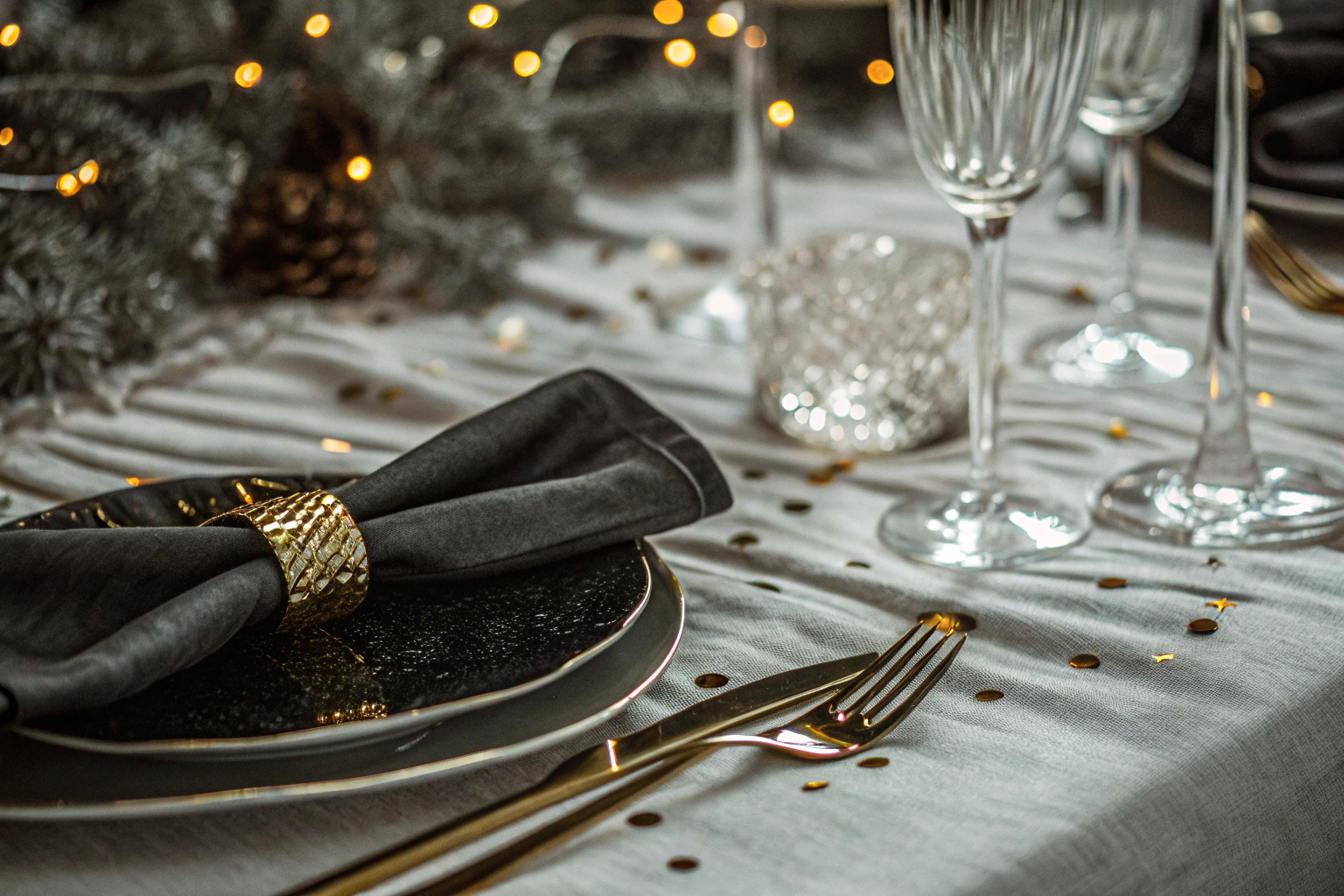 Detailaufnahme von elegant dekorierten Tischen mit goldenen und schwarzen Elementen. Elegante Tischdekoration für Silvester