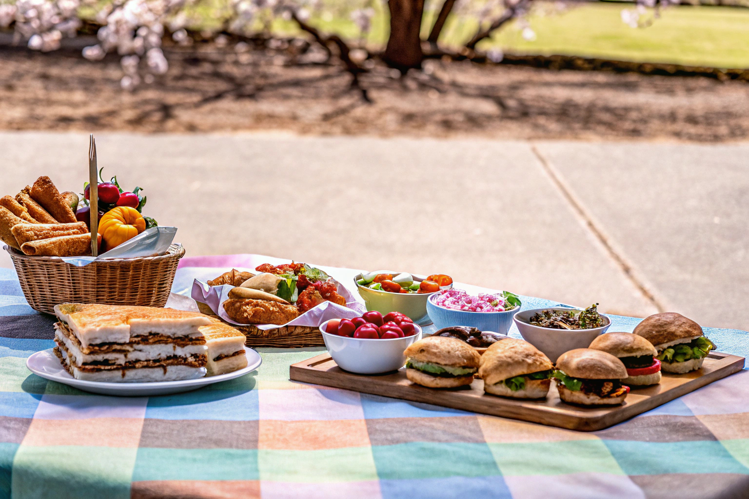 Ein gedeckter Picknicktisch im Park mit verschiedenen Speisen, darunter Sandwiches, Salate und Desserts. Picknicktisch mit Speisen im Park