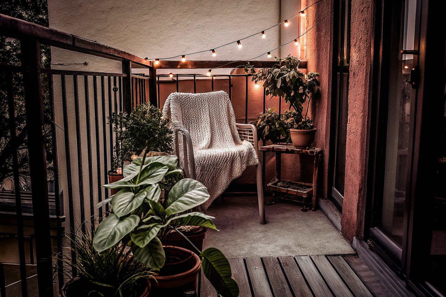 Ein gemütlich dekorierter Balkon mit Pflanzen und Lichterketten. Gemütlicher Balkon mit Pflanzen und Lichterketten