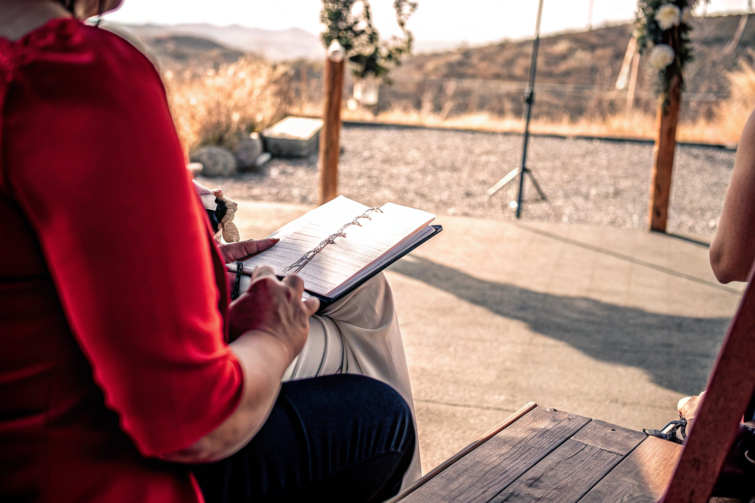 Ein Hochzeitsredner, der in einem Buch blättert und Notizen macht, während er auf eine malerische Landschaft blickt. Inspiration für Hochzeitsreden