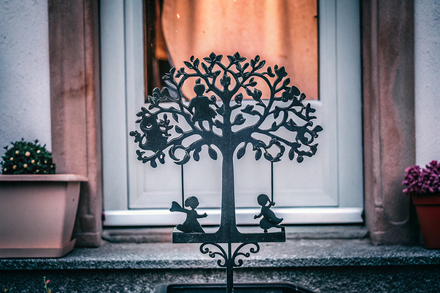 Ein kunstvoller Metallaufsteller mit einem Baum und Kindern auf einer Schaukel Metallaufsteller Baum mit Kindern auf Schaukel