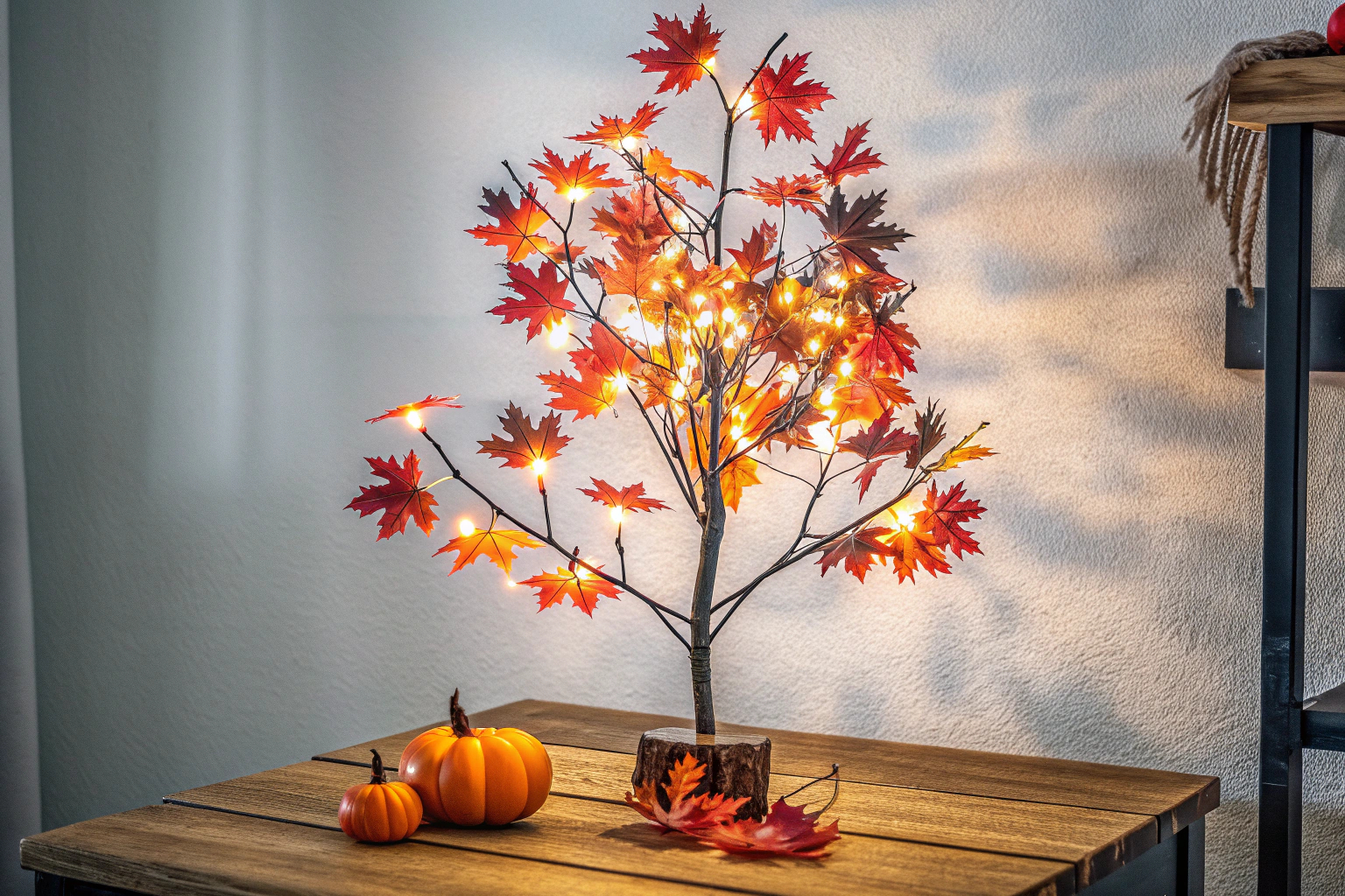 Ein Lichterbaum mit Ahornblättern, der auf einem Tisch steht und den Raum in warmes Licht taucht. Lichterbaum mit Ahornblättern als dekoratives Element