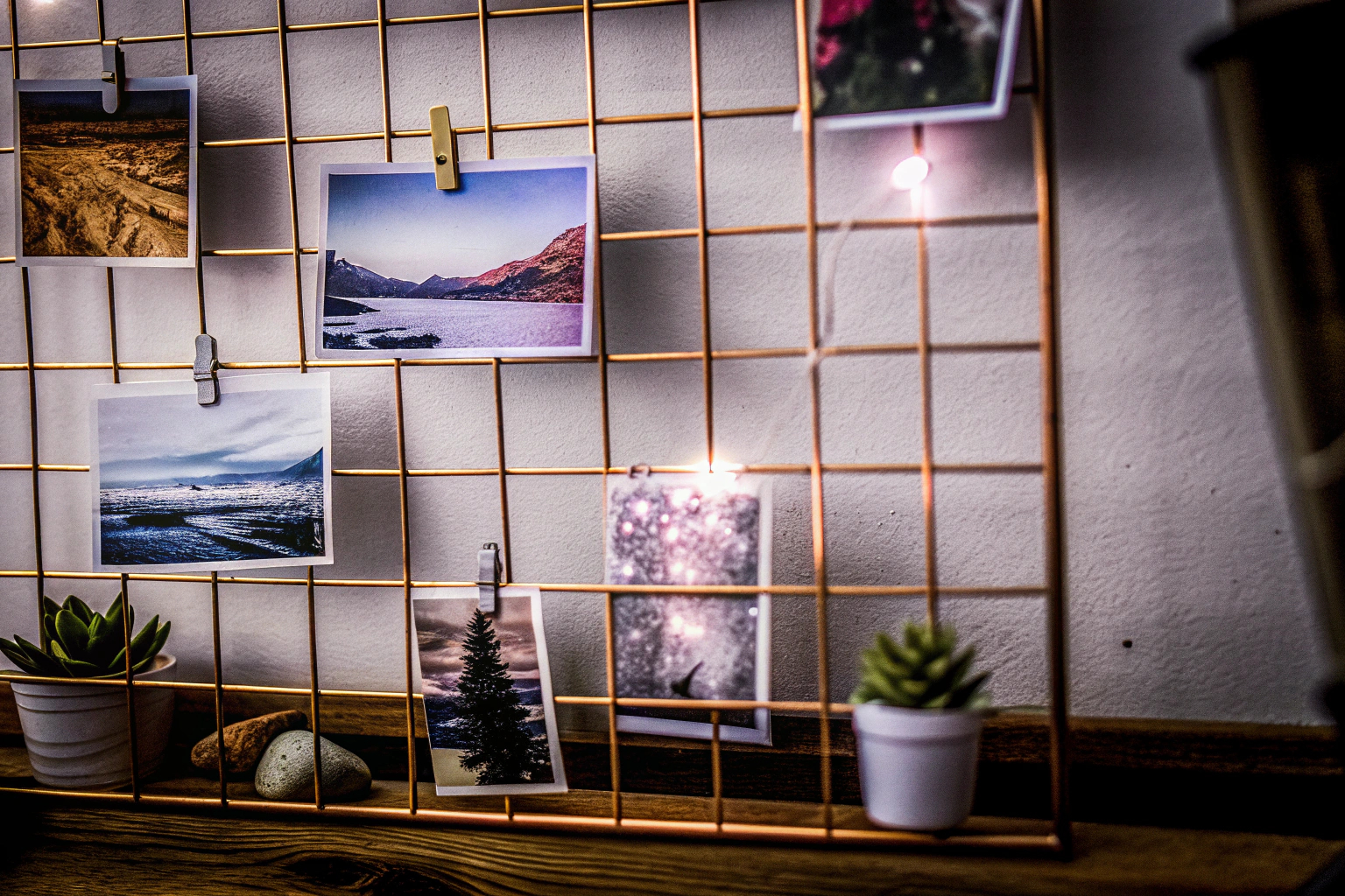 Ein Metallgitter, an dem Fotos und kleine Dekorationen befestigt sind. Metallgitter Fotowand