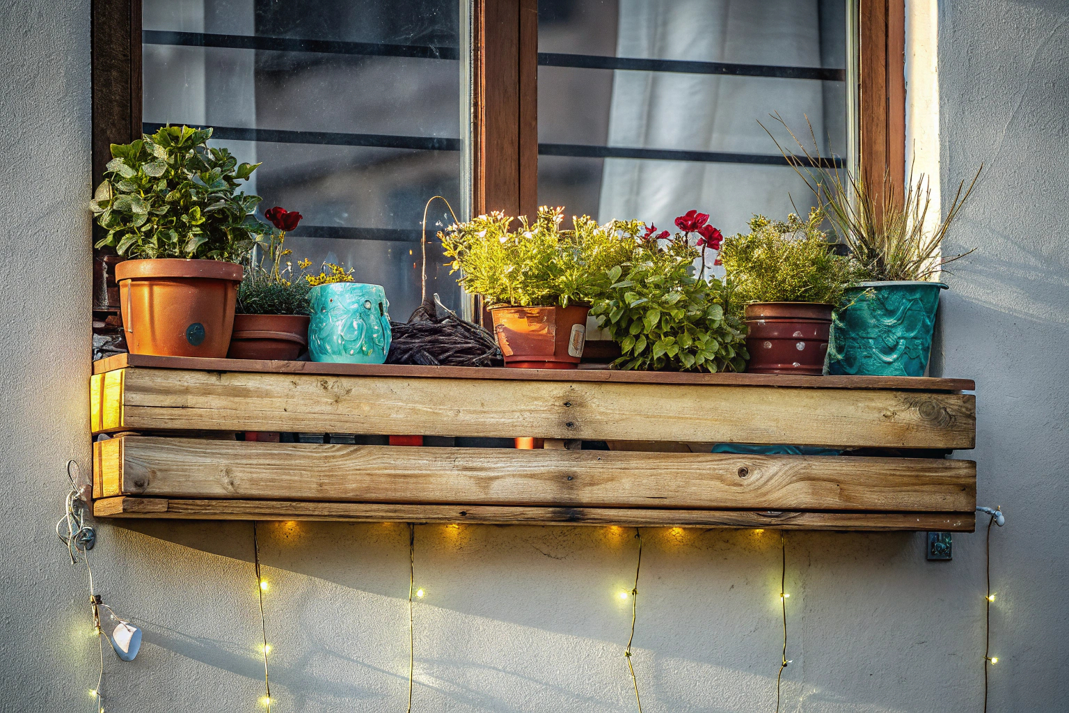 Ein rustikales Wandregal auf einem Balkon mit Pflanzen und Dekorationen. Rustikales Wandregal auf Balkon