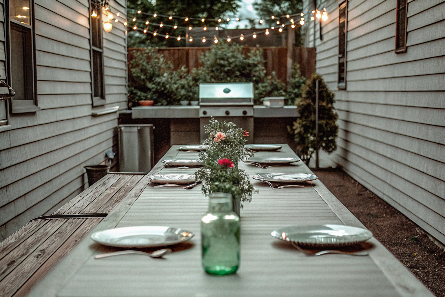 Ein wunderschön dekorierter Garten für eine Grillparty, mit Lichterketten und thematischer Tischdekoration. Garten für Grillparty dekoriert mit Lichterketten
