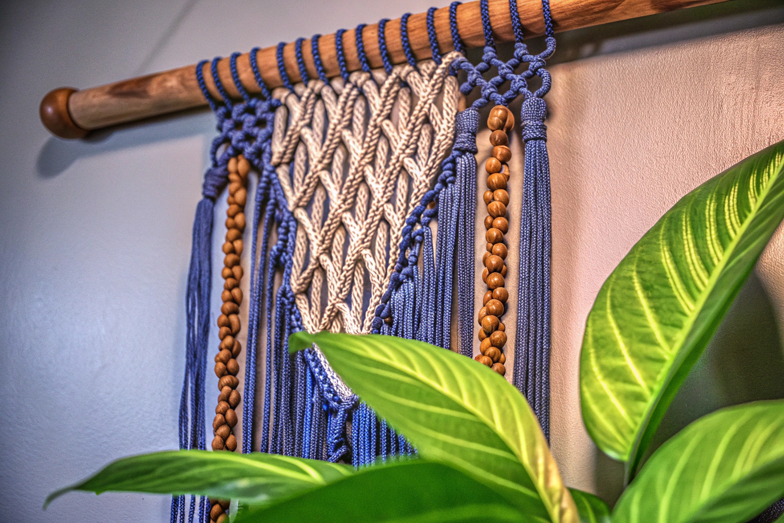 Makramee-Wandbehang mit grünen Blättern und Holzperlen an einer Wand, die eine entspannte Boho-Atmosphäre schafft. Makramee Wandbehang in Boho-Stil