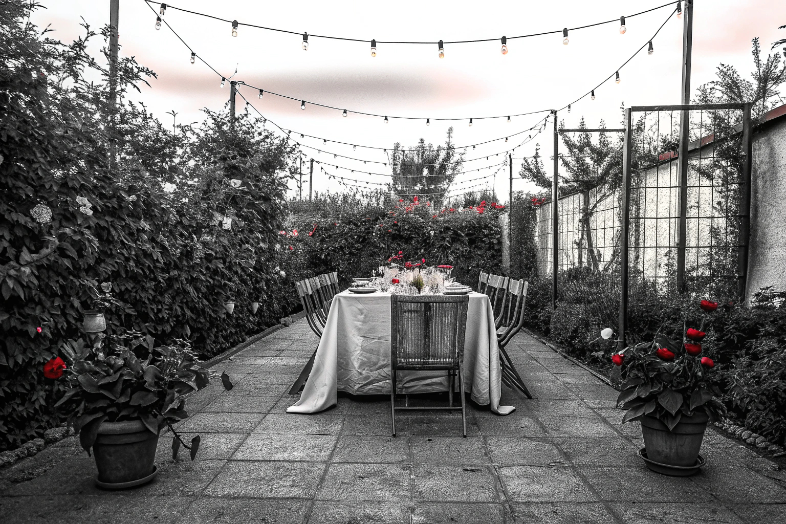 Stimmungsvolle Gartenszene mit Lichterketten und gedecktem Tisch im Freien. Einladungskarten für Gartenparty