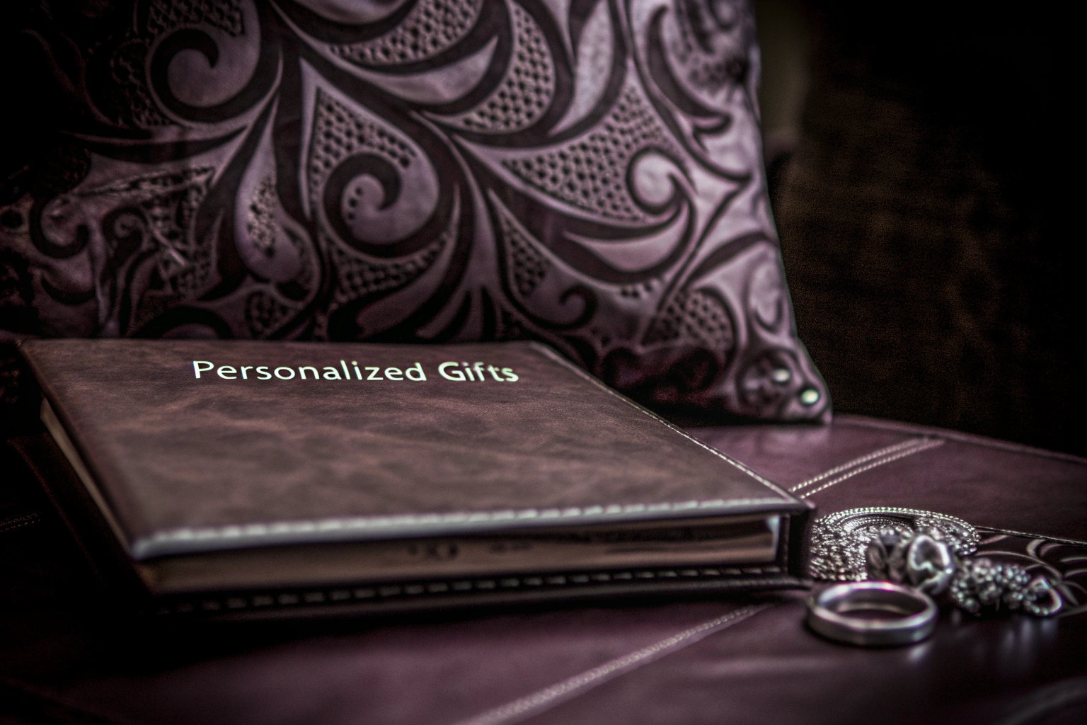 Verschiedene personalisierte Geschenke auf einem Tisch arrangiert, darunter ein Fotoalbum, ein graviertes Schmuckstück und ein individuelles Kissen. Personalisierte Geschenke Arrangements